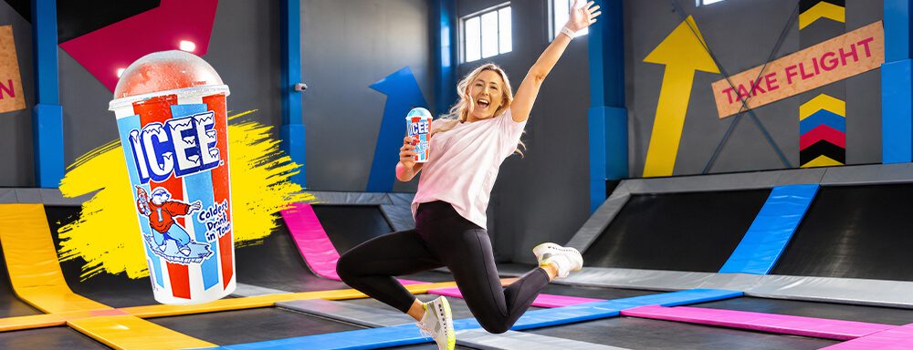 woman jumping on bounce trampoline holding an Icee slushy